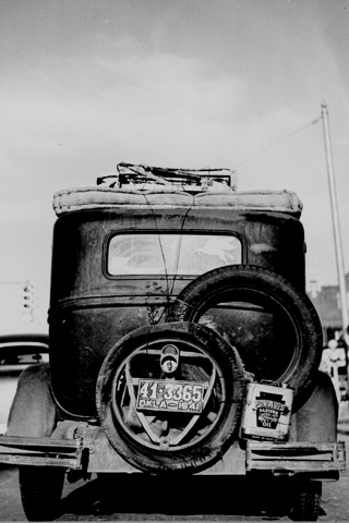 Rear view of an “Okie's” Car heading West as part of the “Dust Bowl” migration of American farmers (1941) NARA-Image, ID=532820. Public Domain.